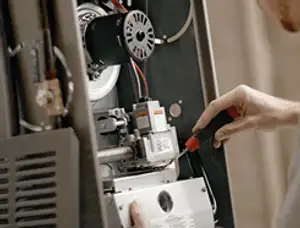 Furnace repair technician inspecting internal components and wiring in Evansville, IN