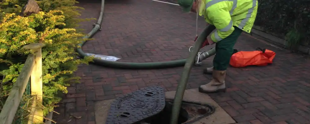 Septic tank cleaning technician servicing a septic tank with a vacuum hose in Evansville, IN